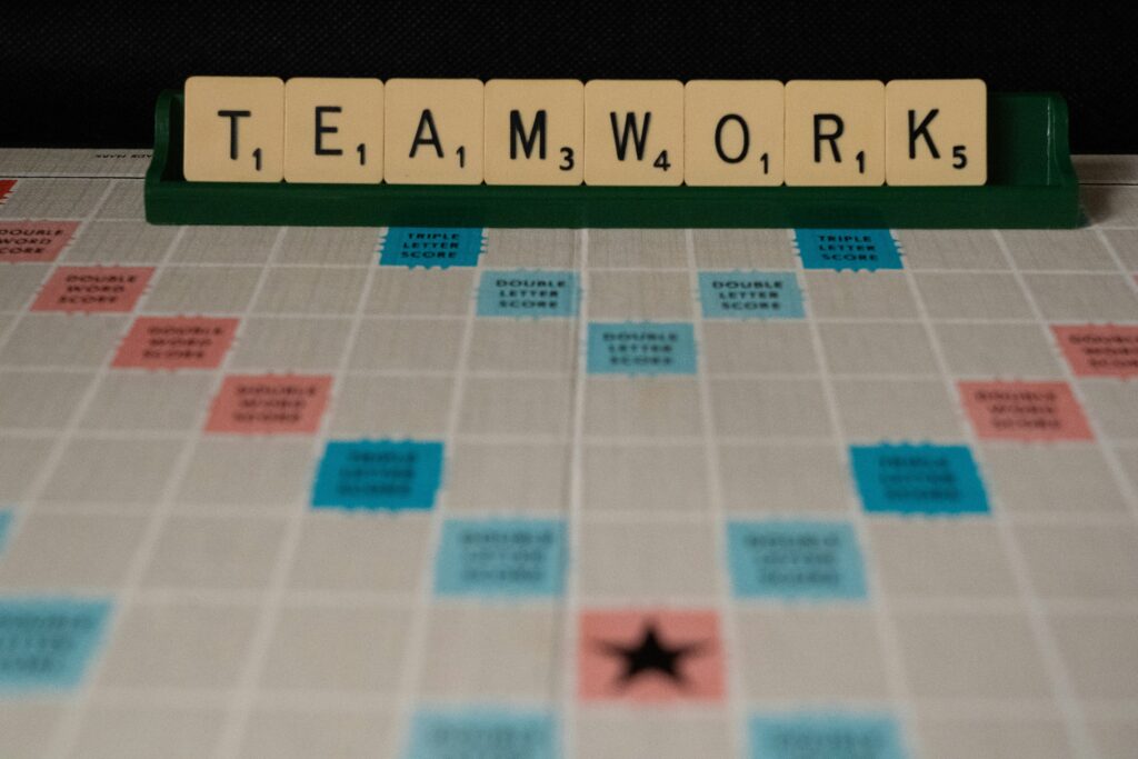 Scrabble board with tiles on holder spelling TEAMWORK