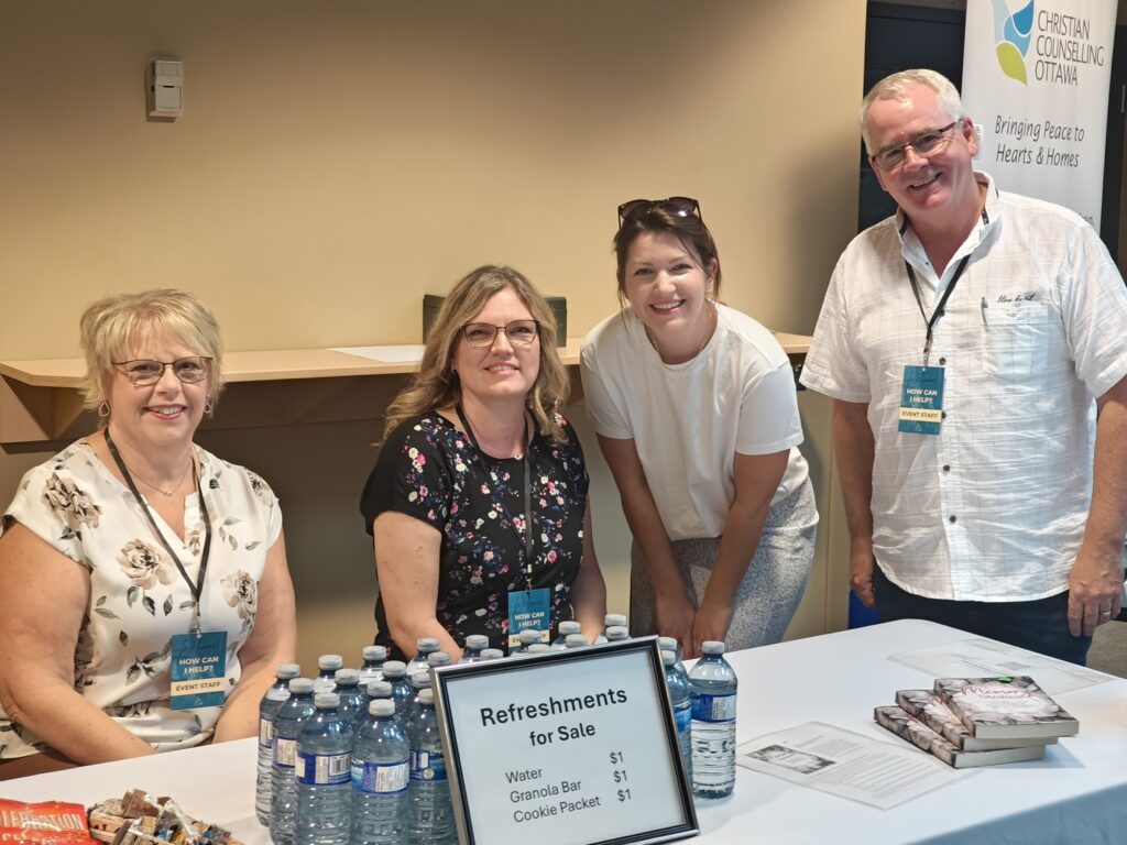 four volunteers at the CCO table in the foyer of the Met Church 