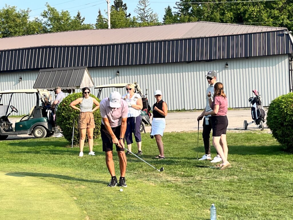 a golfer chipping from just off the green with five others watching on