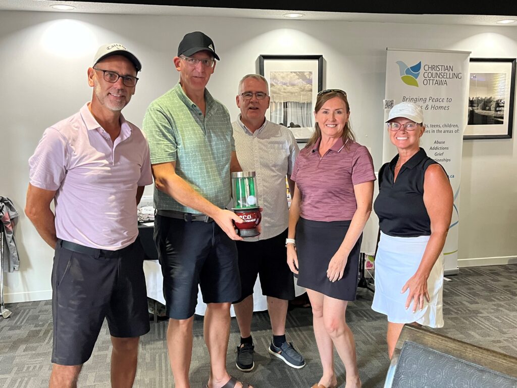 winning golf team of two men and two women holding trophy with tournament executive director