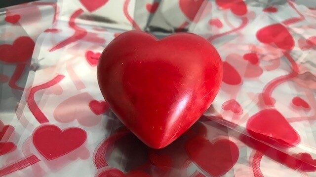 Image of a red stone heart on a layer of cellophane with red heart and streamer pattern