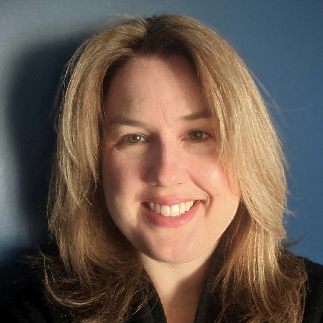 a headshot of a smiling woman with shoulder length blonde hair wearing a black top