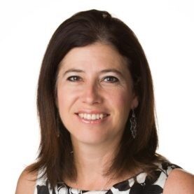 a headshot of a smiling woman with shoulder length dark brown hair wearing a sleeveless black and white patterned top